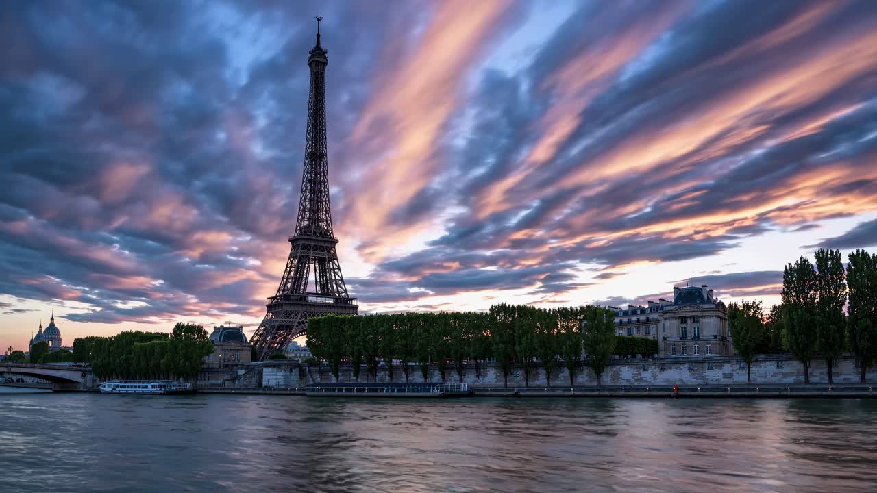 A wide-angle video shot captures the Eiffel Tower at sunset, with dramatic clouds and reflections
