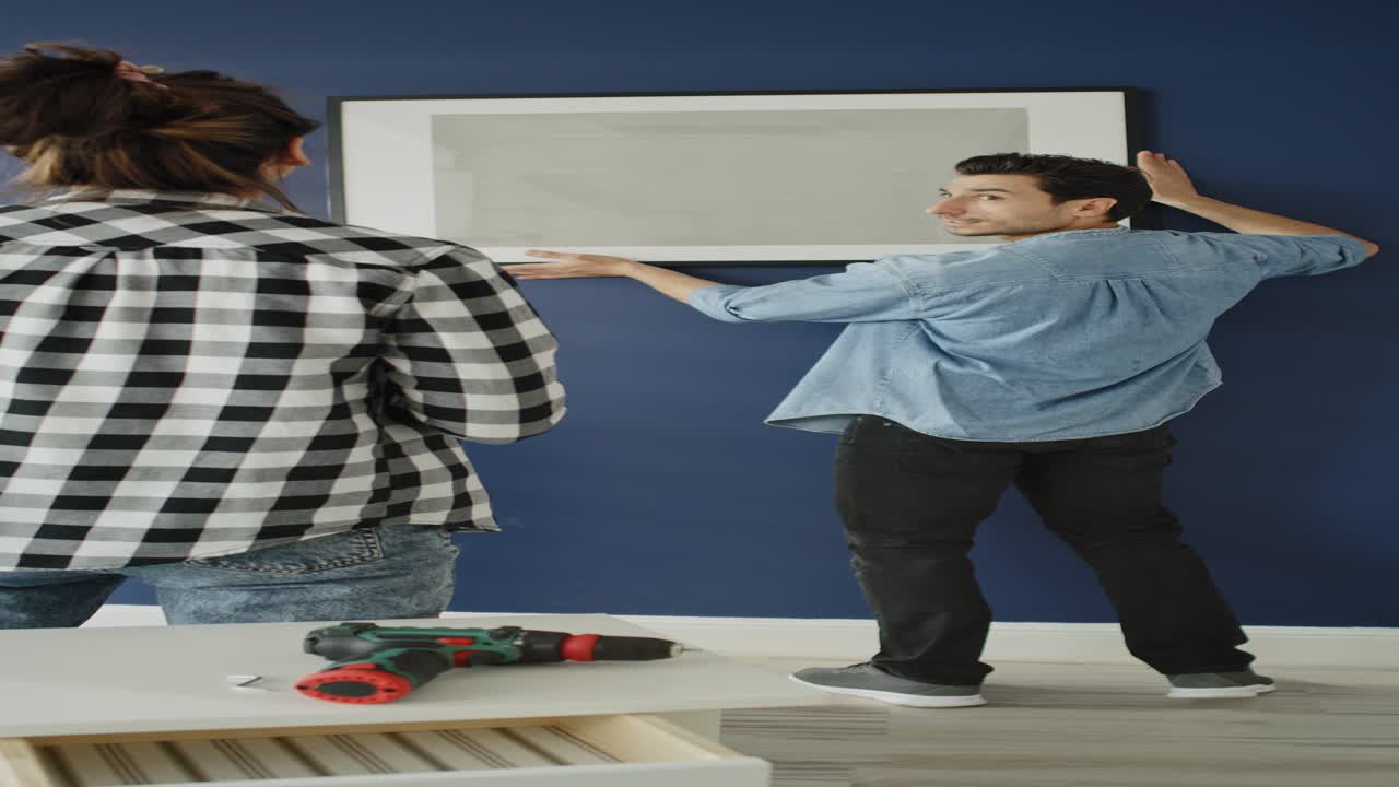 Vídeo de casal pendurando um quadro em casa nova