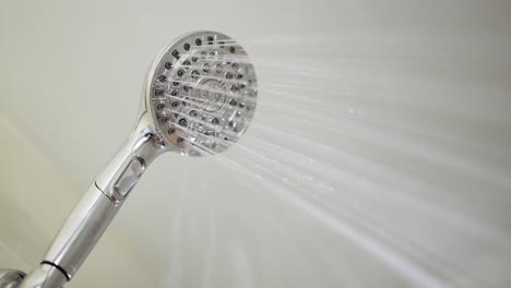 male hand flips a switch on the running shower head to turn on the jets harder