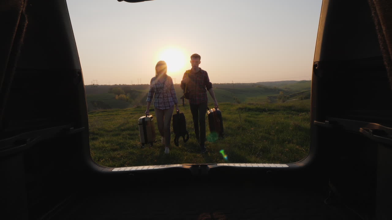 A Pair Of Tourists Loads Bags In The Trunk Of A Car