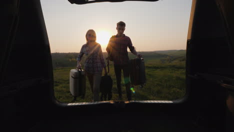 A-Pair-Of-Tourists-Loads-Bags-In-The-Trunk-Of-A-Car