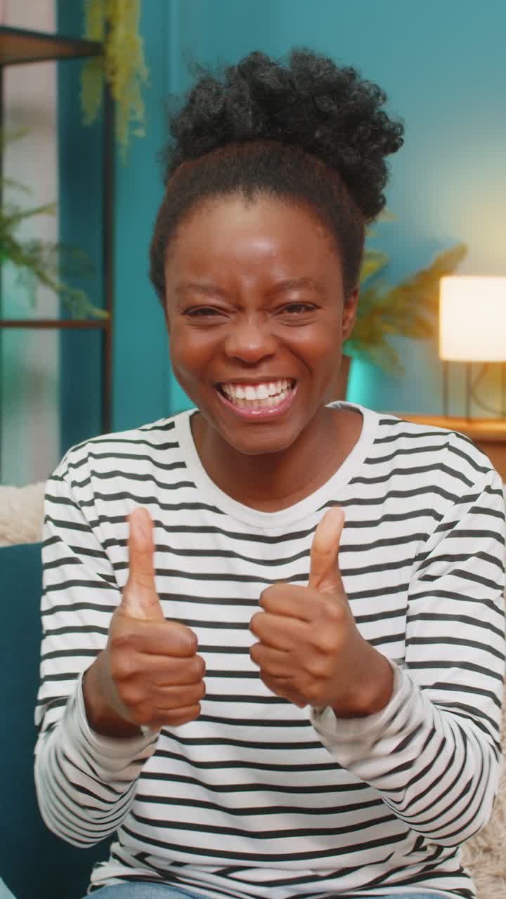 African american woman celebrating victory sofa jumping hands raised joyful energy success indoors