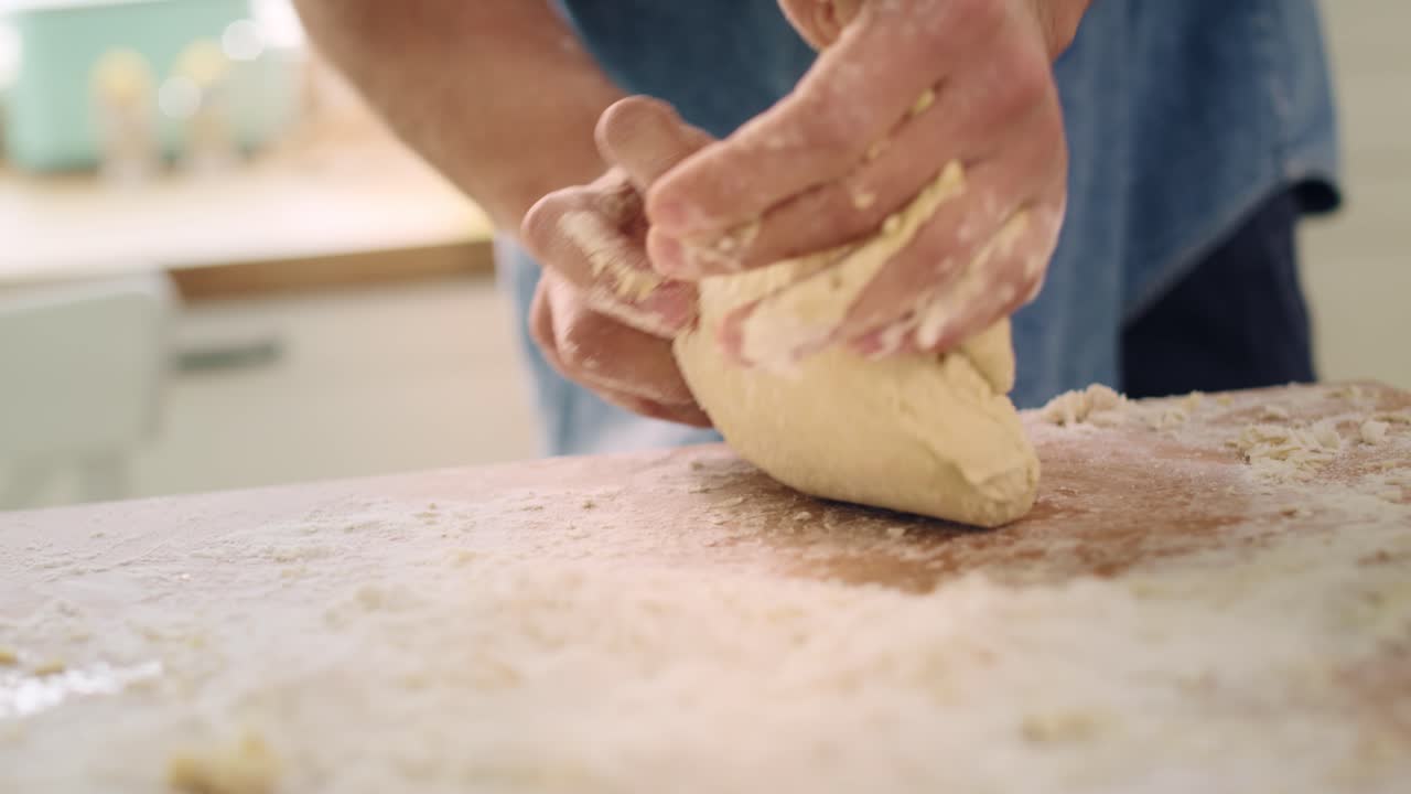 Handheld video shows of man&rsquo;s hands kneading the dough