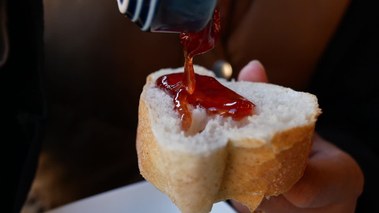 Close-up of a person spreading jam on bread