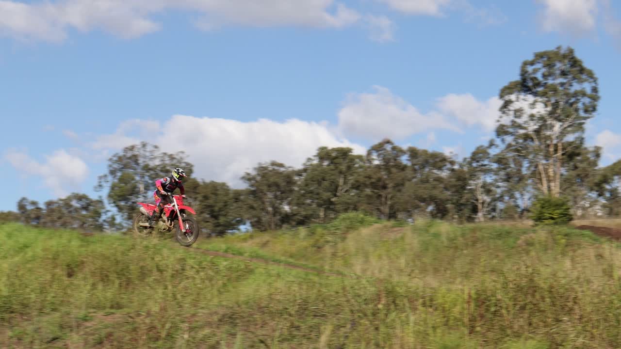 motociclista viaja a través de un campo cubierto de hierba y árboles