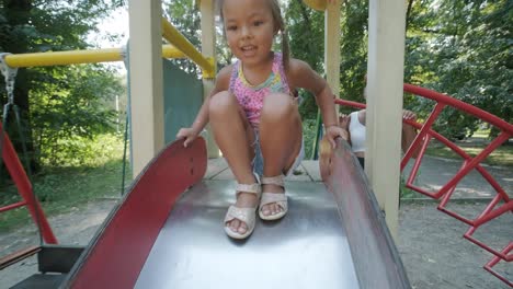 pregnant mother watching daughter play on slide at playground