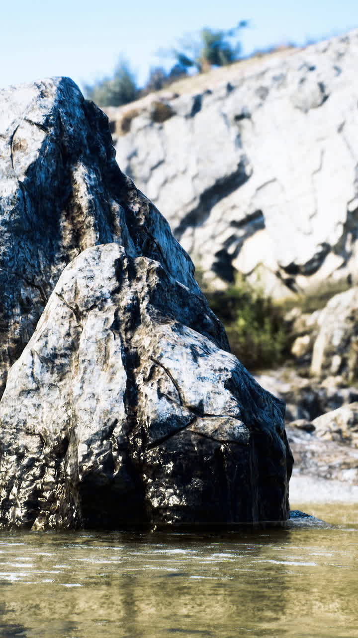 Grande formazione rocciosa vicino ad acque calme circondata da scogliere e alberi