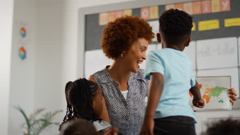 multi-cultural elementary school pupils with female teacher asking question in geography class