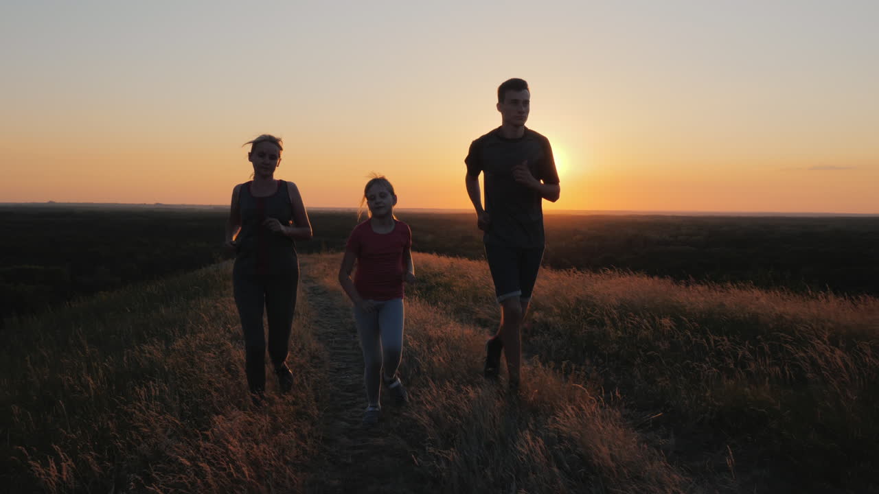 un niño pequeño con una pareja corriendo al aire libre en un lugar pintoresco al atardecer