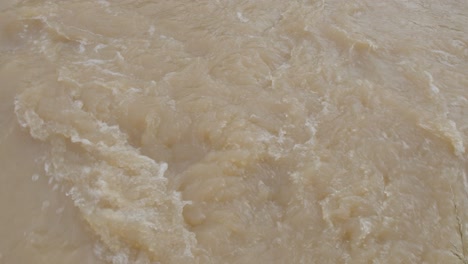 tiro inclinado hacia arriba de un arroyo inundado con agua marrón fangosa y corriente fuerte - kentucky