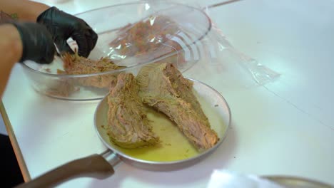 manos con guantes negros triturando carne usando un tenedor en la cocina - primer plano, ángulo alto