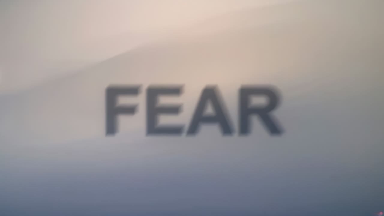 Vippende, fed FEAR med store bogstaver, der flytter sig, toner ud og sløres på en gradientbaggrund, af lysflare