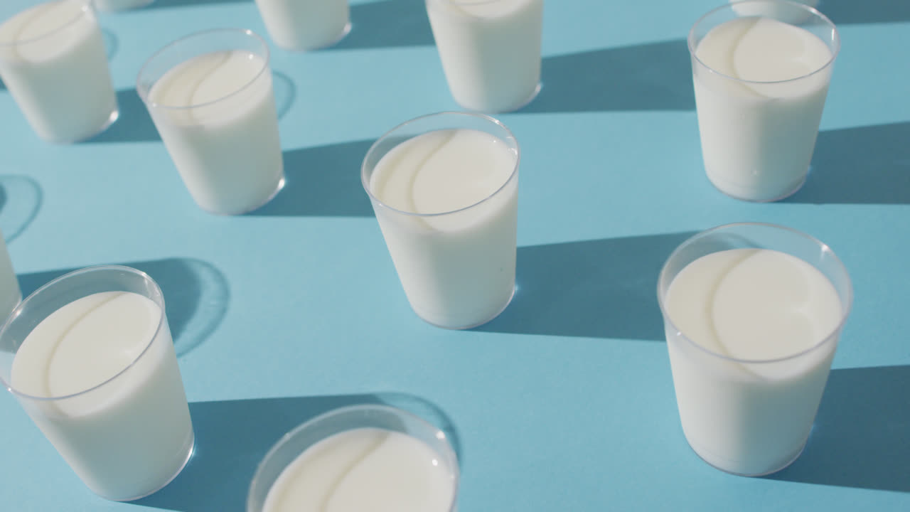 video de una fila de vasos de leche sobre un fondo azul