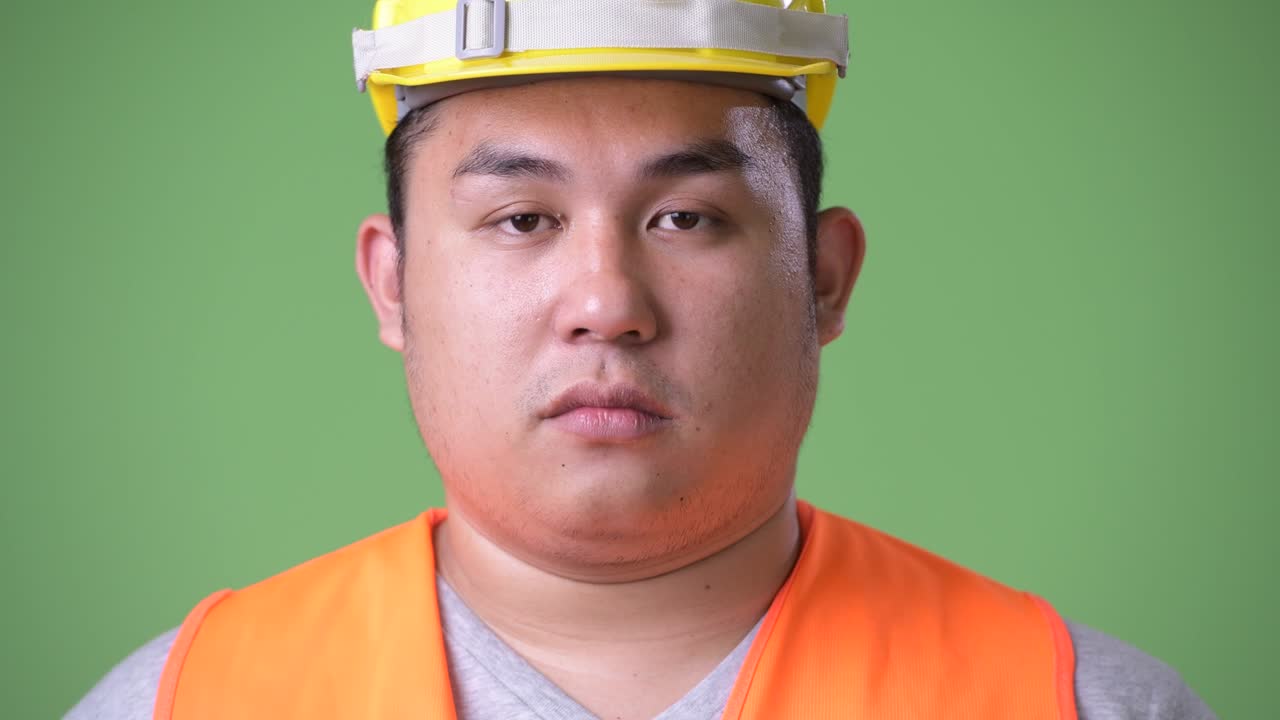 젊은 잘생긴 과체중 아시아인 남자 건설 노동자 초록색 배경