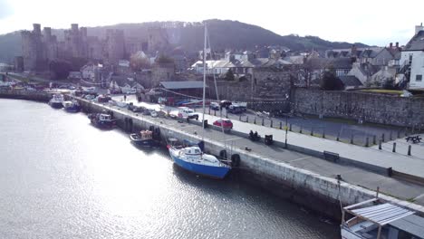 idyllic conwy castle and harbour fishing town boats on coastal waterfront aerial pull away low angle