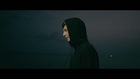 person in hoodie at dusk by the sea