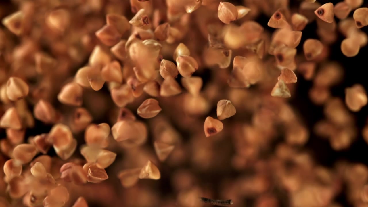 Grani di grano saraceno che cadono in super rallentatore su sfondo nero