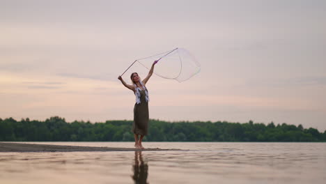 a young girl artist shows magic tricks using huge soap bubbles. create soap bubbles using sticks and rope at sunset to show a theatrical circus show