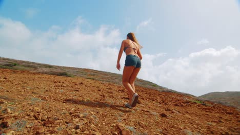 Hinter-Mädchen-Wandern-Berg-In-Shorts-Und-Bikinioberteil,-Low-Angle-Slowmo