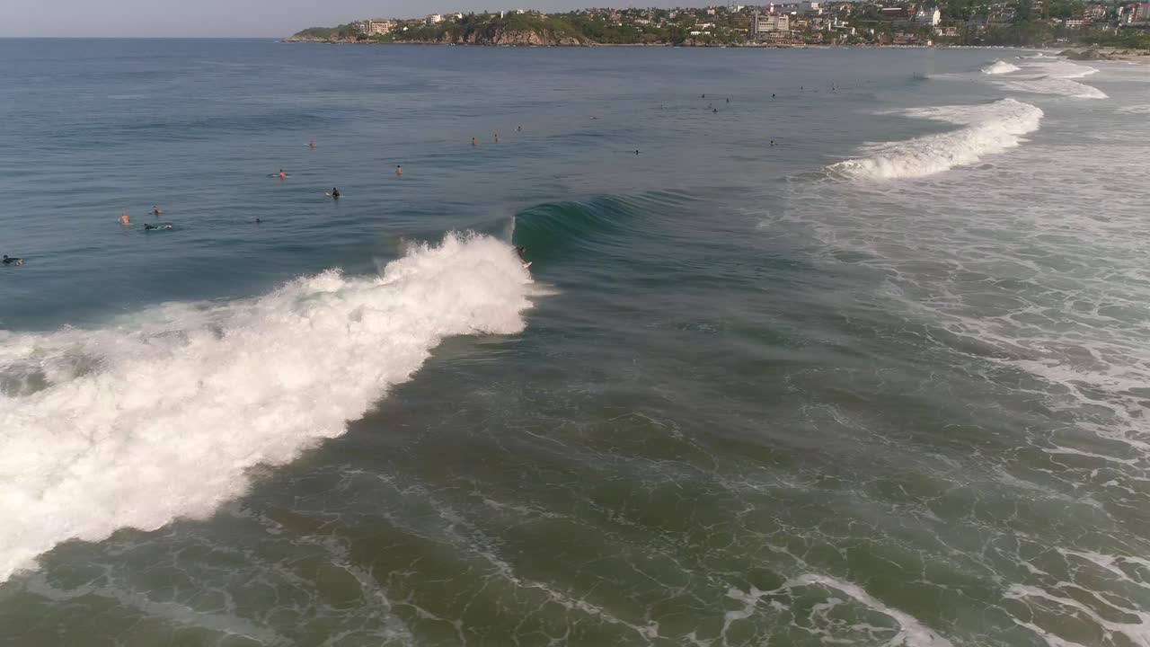 Ripresa aerea con drone di un surfista che cavalca un'onda tubolare e cade sulla spiaggia di Zicatela, Puerto Escondido, Oaxaca