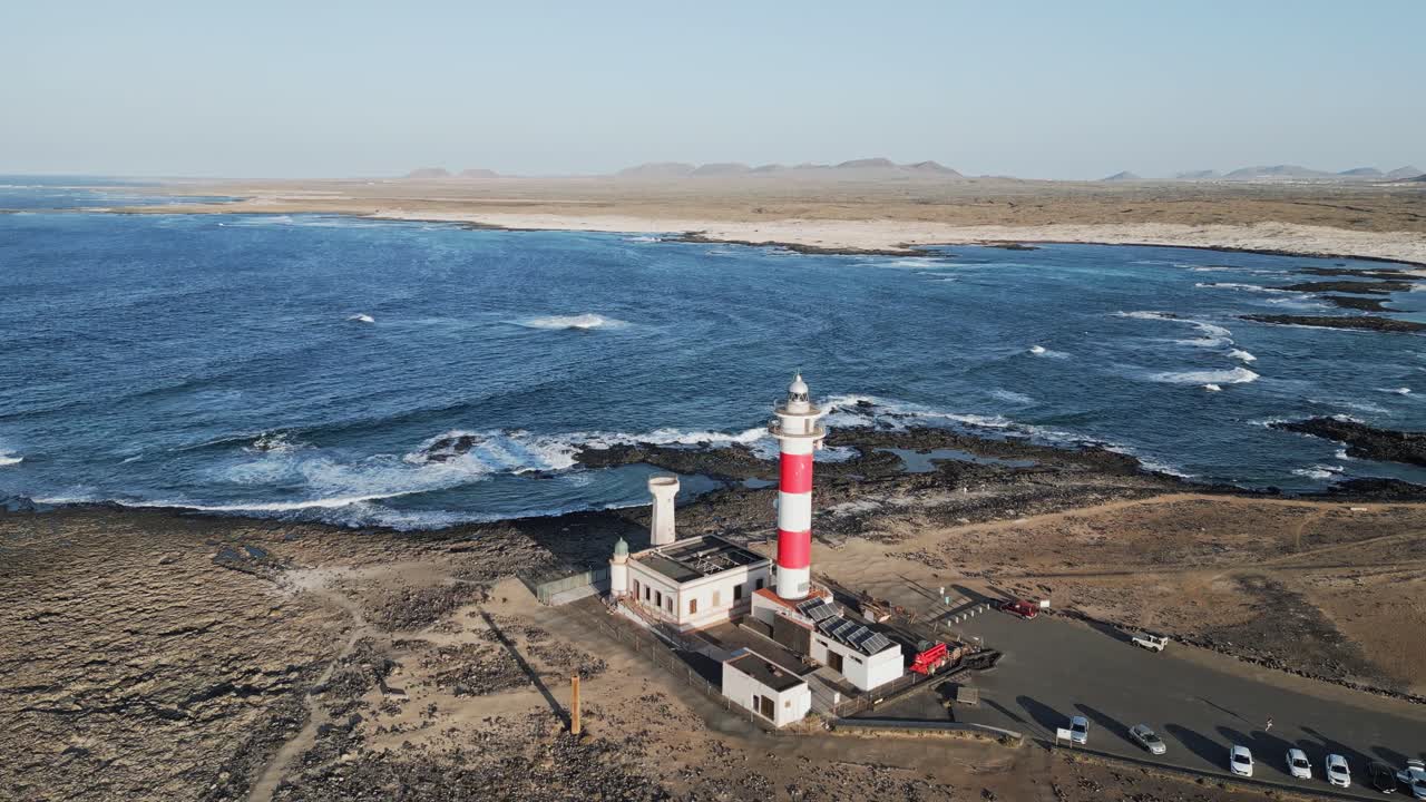 Top-down drone view of El Tostón Lighthouse in El Cotillo, Fuerteventura, surrounded by volcanic rocks and Atlantic waves.