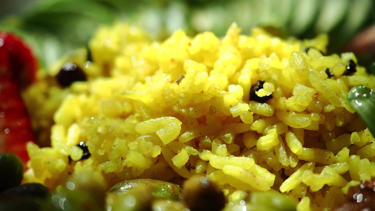 Primer plano de arroz de cúrcuma amarillo vibrante servido en una hoja de plátano.