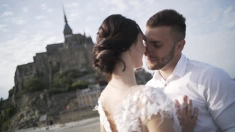 couple kissing in front of mount saint michel