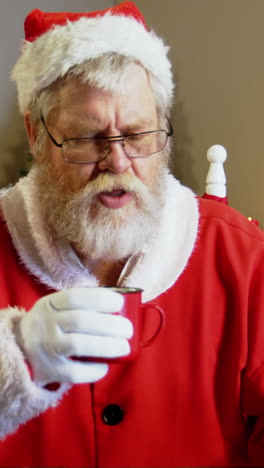 santa claus relajándose en una silla y tomando café