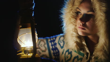 young woman with an oil lamp in the dark fearfully looking around