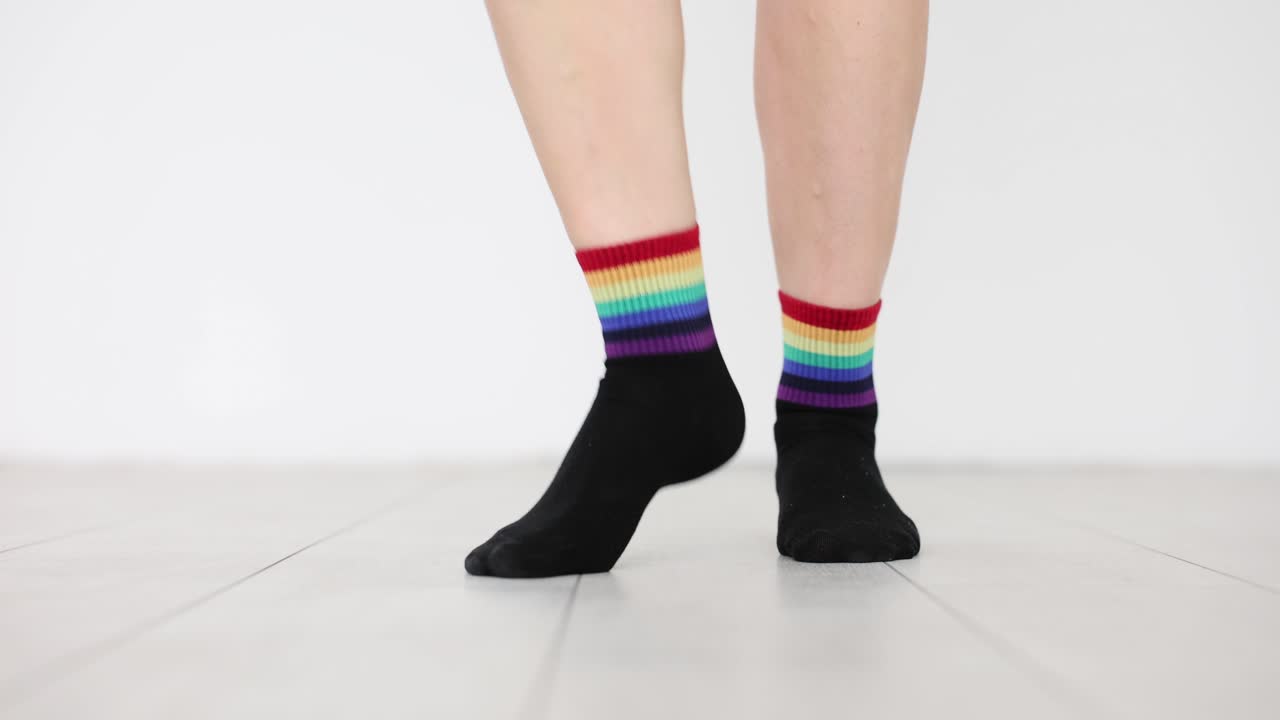 Piedi che fanno un passo con calzini neri e l'immagine della bandiera arcobaleno