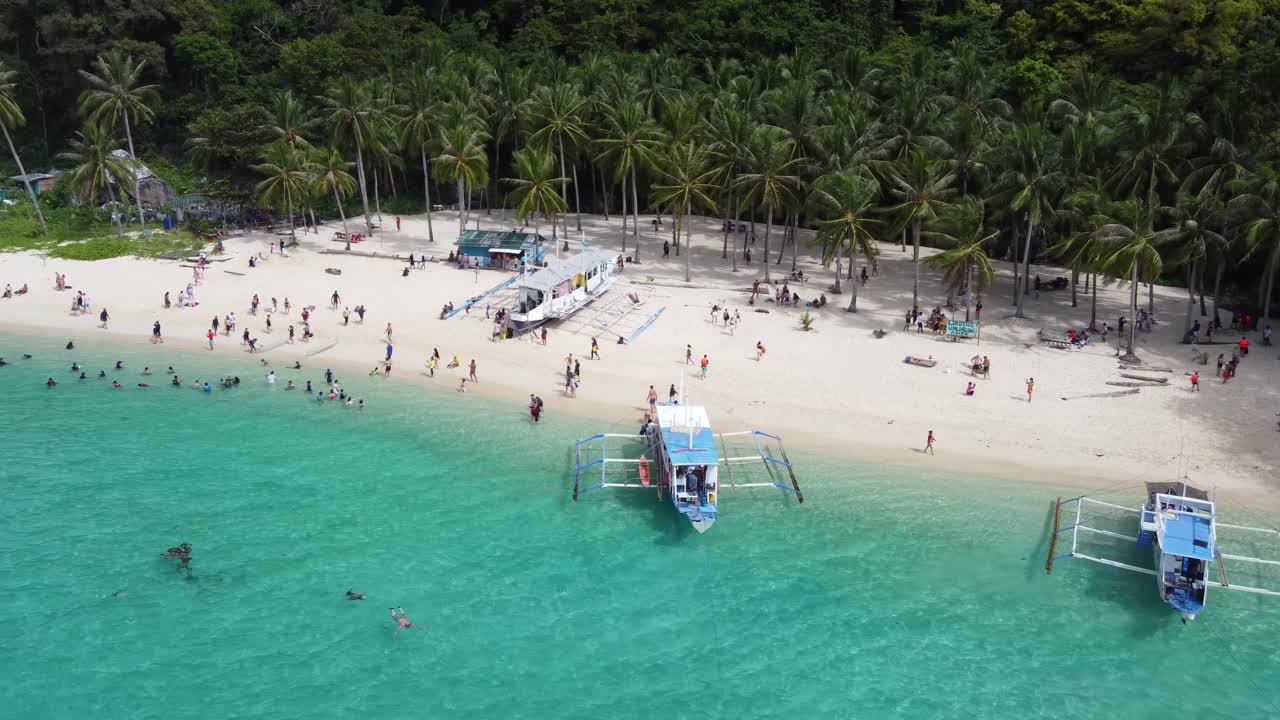 열대 7개의 커맨도 해변에서 사람들이 아쿠아마린  ⁇ 은 물에서 수영하고 배경에는 관광 보트와  ⁇ 나무가 있습니다. 엘 니도