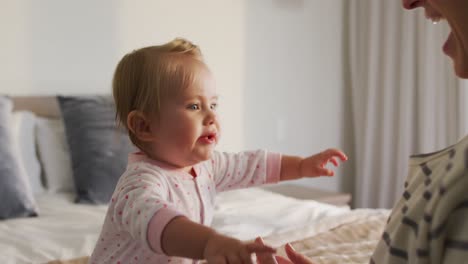 madre caucásica feliz sosteniendo y besando a su bebé en casa