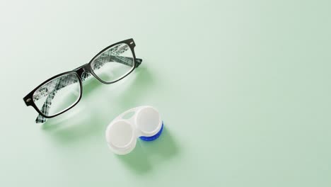 Video-of-pair-of-glasses-and-contact-lenses-case-on-green-background-with-copy-space