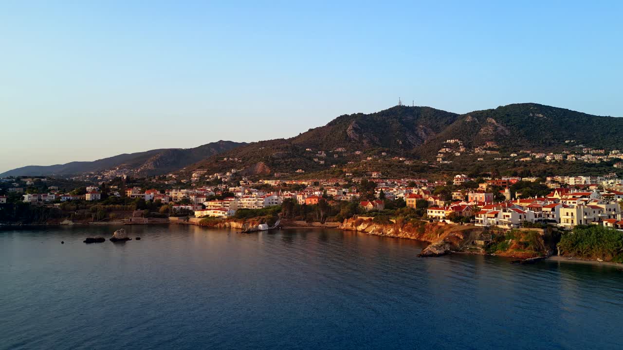 Aerial shot of villas on the coast of Mytilene, Lesvos island, Greece, with the sunset glowing on them and a tranquil blue ocean.