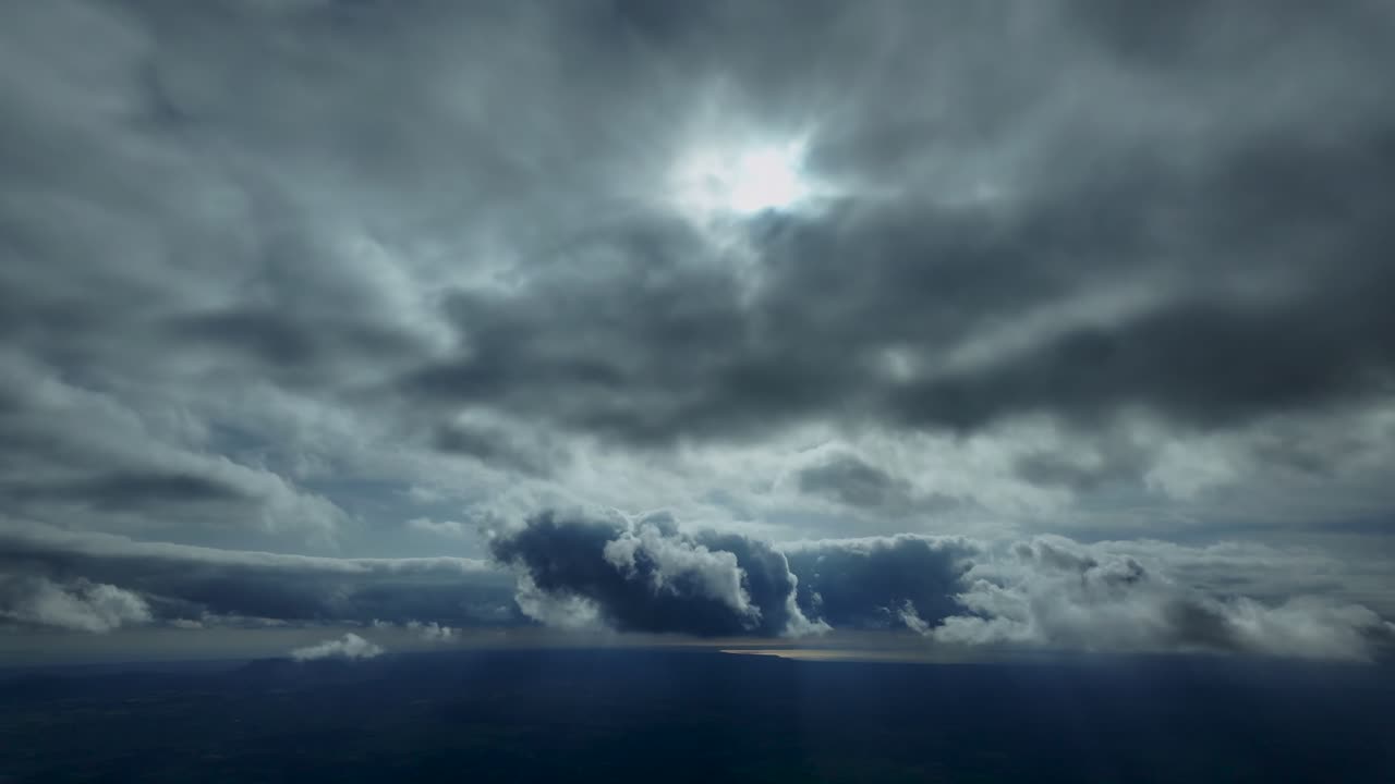 Pilot’s eye view captured from a jet cockpit whilem flying through ethereal clouds, withy a veiled sun above, and the sea in the background