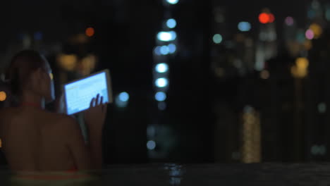 Kuala-Lumpur-night-view-and-woman-with-pad-in-pool