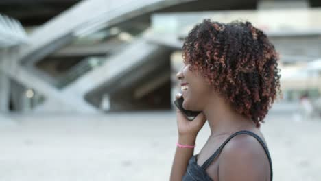 Side-view-of-young-woman-talking-on-smartphone-during-stroll