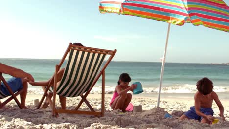 une famille heureuse se repose sous un parasol.