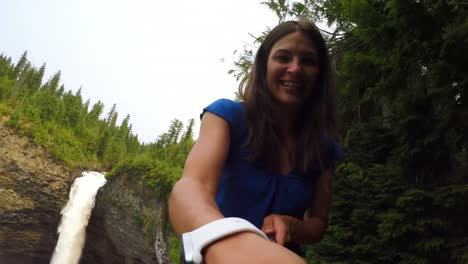 Woman-smiling-at-the-camera,-waterfall-in-background-4k