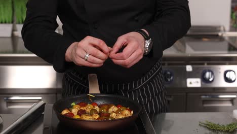 chef preparing a dish with vegetables and herbs