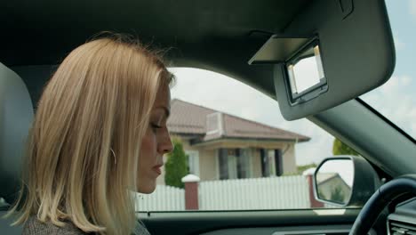 woman applying lipstick in car