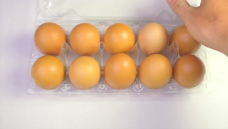 man takes eggs from container on white background