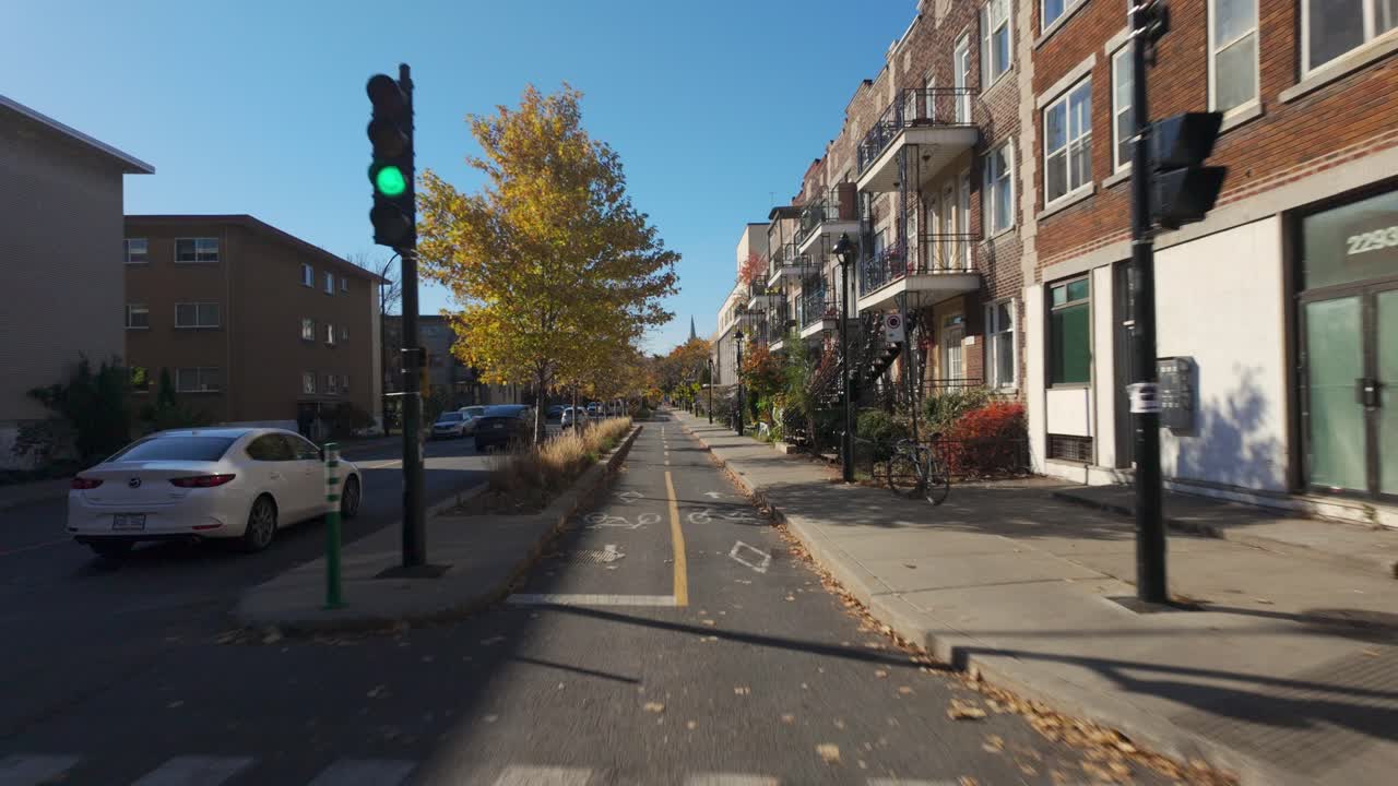 A view of a sunny residential street in Plateau District with cars and autumn colors, biking pov