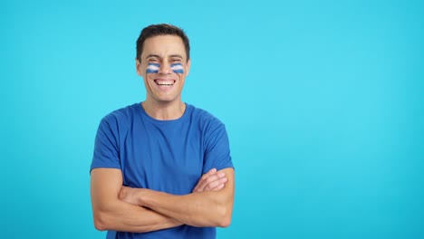 man standing with salvadoran flag painted on face smiling