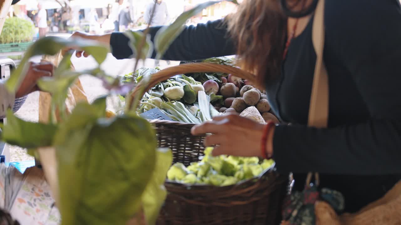 Woman adds lettuce and veggies to rustic basket