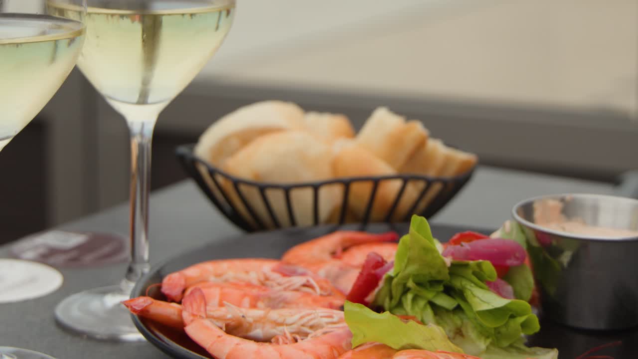Close-up of seafood platter, white wine, and bread on outdoor table with soft natural lighting