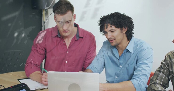 Two colleagues in business pointing at laptop screen and generating data overlays analyzing metrics