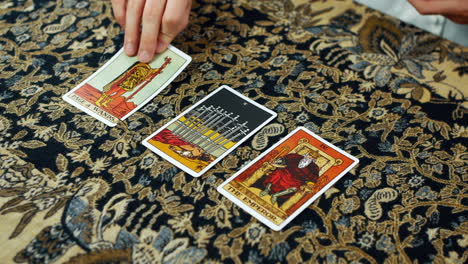 a woman giving a tarot reading with the page of wands the ten of swords and the emperor cards