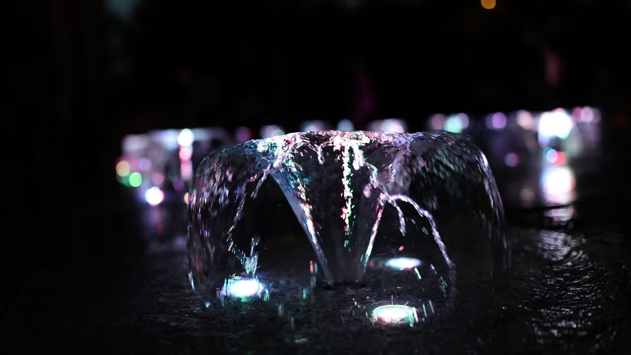 Vibrant Water Splashes Illuminated by Colorful Lights at Night