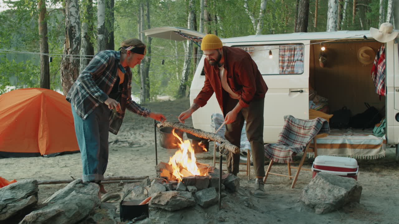 남성 친구 들 이 캠프 불 위 에서 음식 을 요리 하고 있다